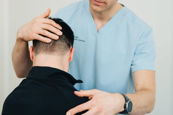 Chiropractor gently examining a patient neck during consultation — Saint Paul Park MN