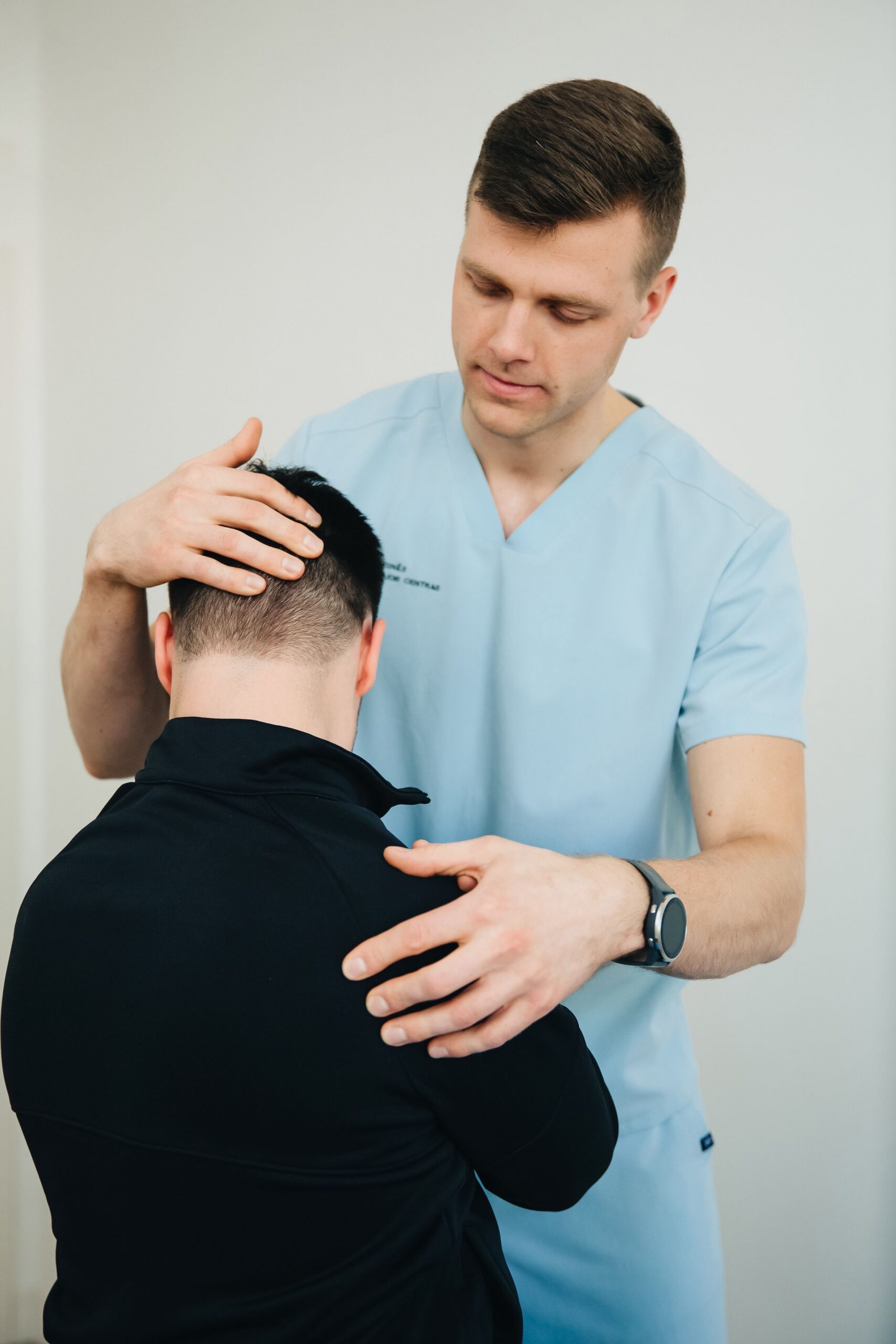 Chiropractor gently examining a patient neck during consultation — Saint Paul Park MN